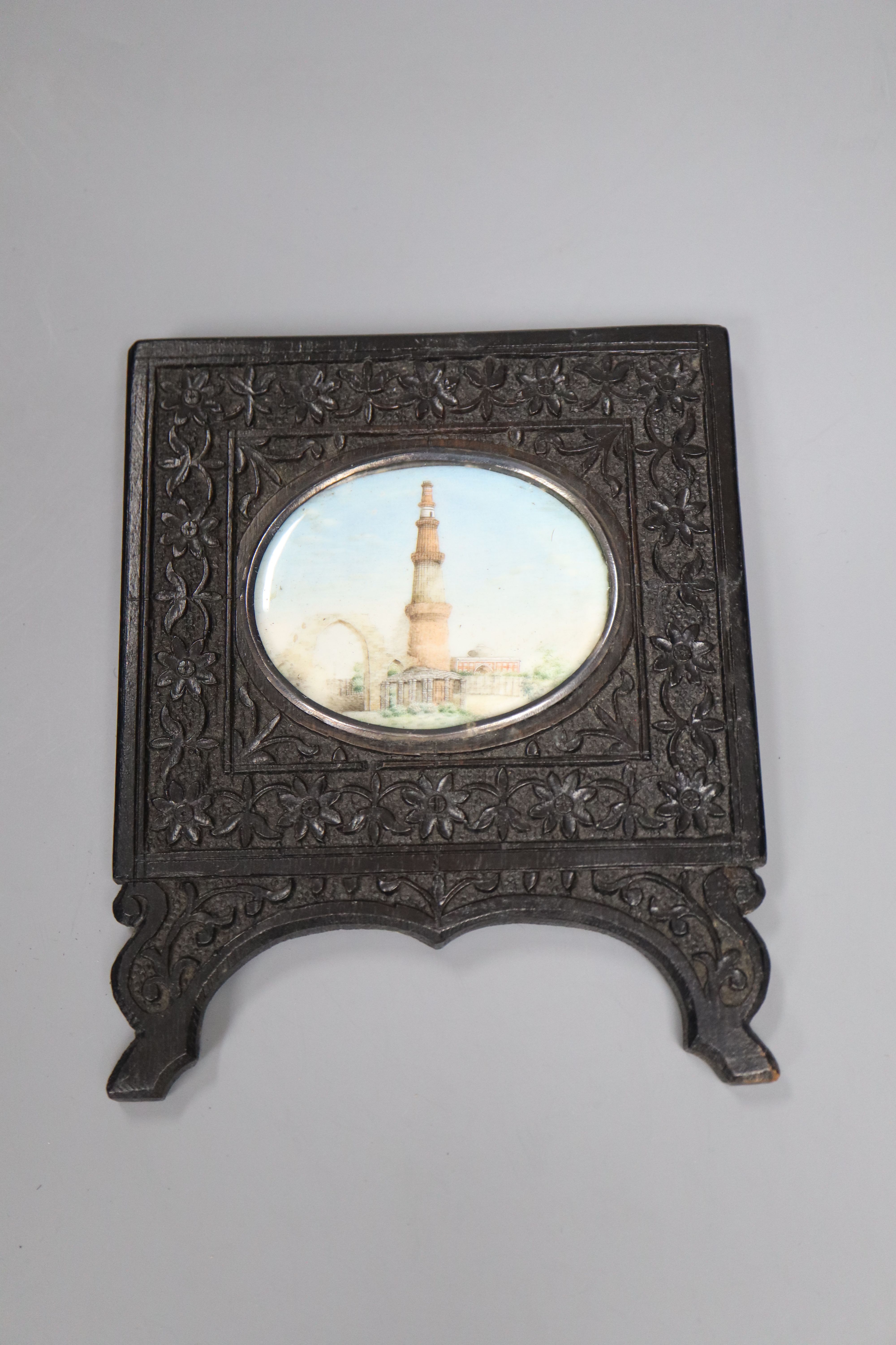A 19th century Indian oil on ivory miniature, The Qutub Minar Tower, 6.5cm wide, in a carved ebony frame